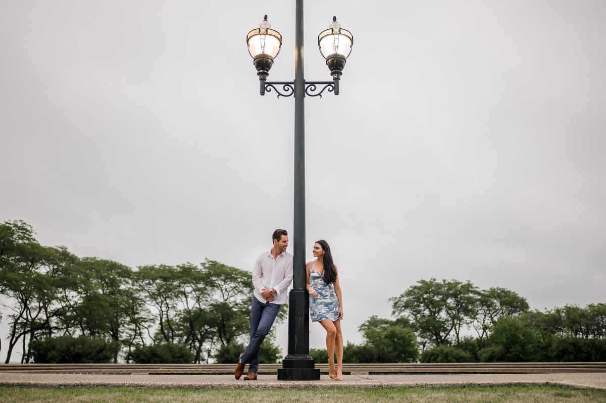 A couple stand by a light pole