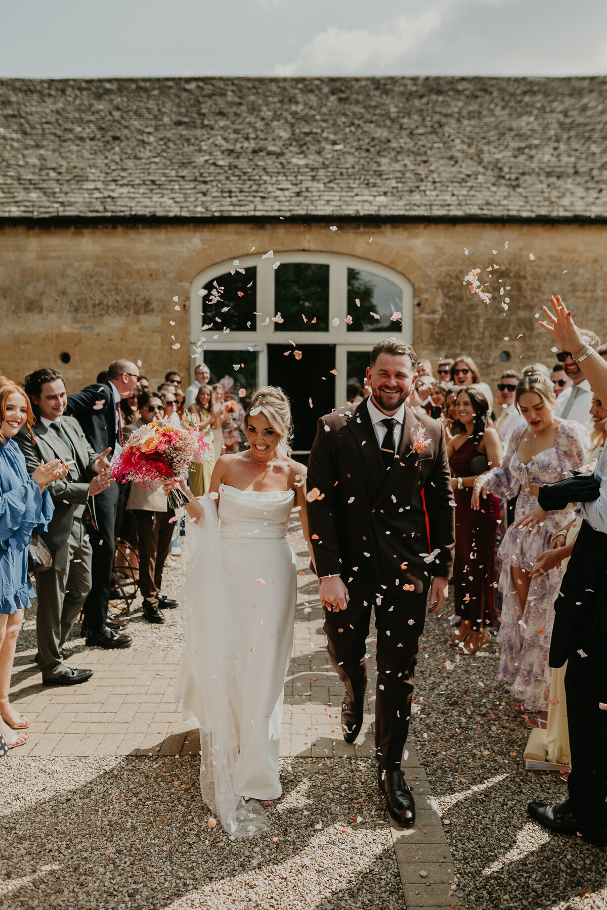 Bride and Groom walk through a tunnel of confetti as they exit their wedding ceremony at Lapstone Barn.