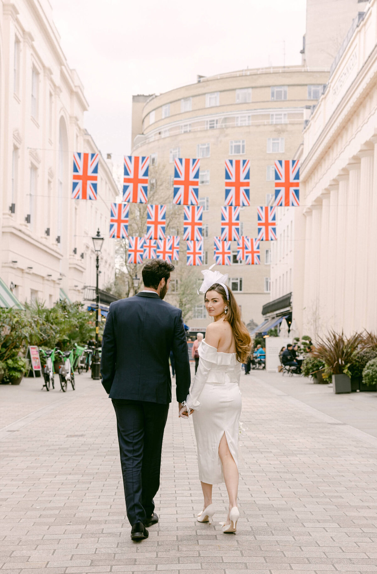 A wedding day photo of the couple walking down a cobble street in London in the United Kingdom