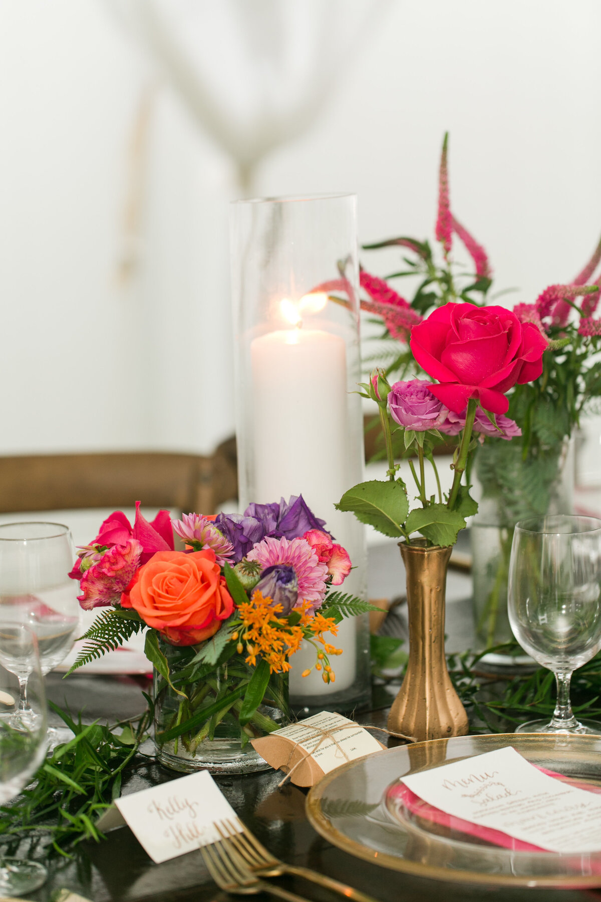 Bright florals in gold vases on wedding reception tables