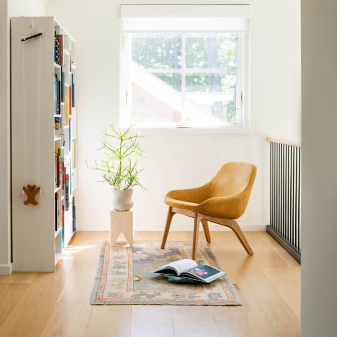 Interior designers in Boston, MA, create a modern reading nook at a new construction home in Hingham with a vintage area rug, lounge chairs, and bookshelves in a kid-friendly design.