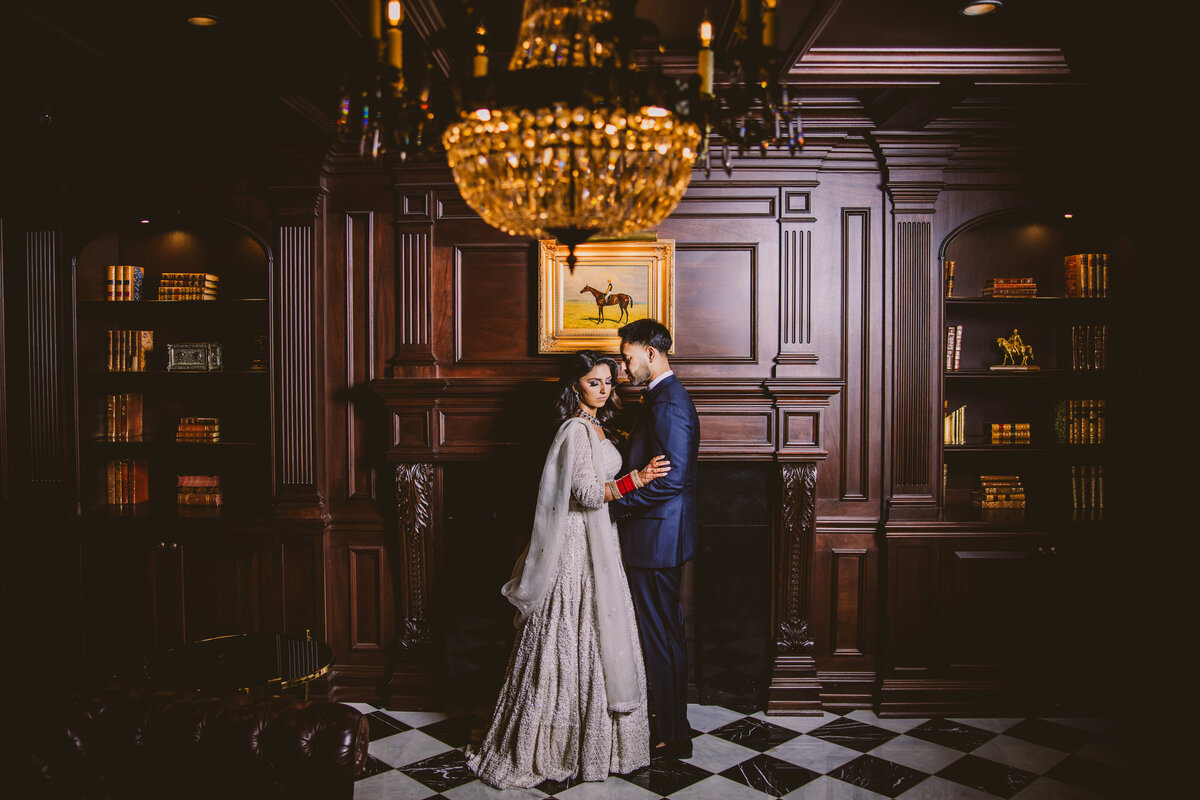 Indian bride and groom share a moment inside a brown room in a moody dark setting at the park chateau in nj