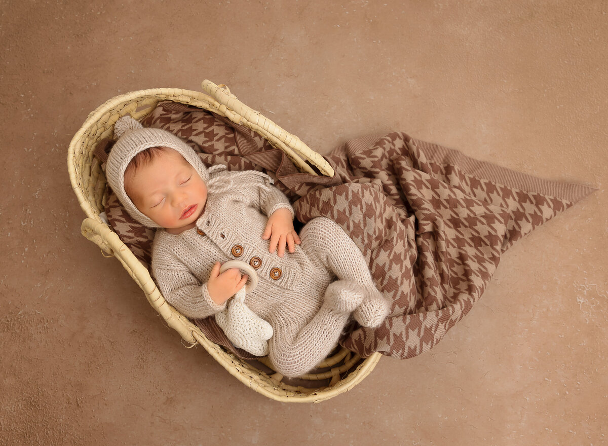 Aerial image of newborn photoshoot. Baby  boy is sleeping in a moses basket laying on his back. Captured by top Brooklyn newborn photographer Chaya Bornstein