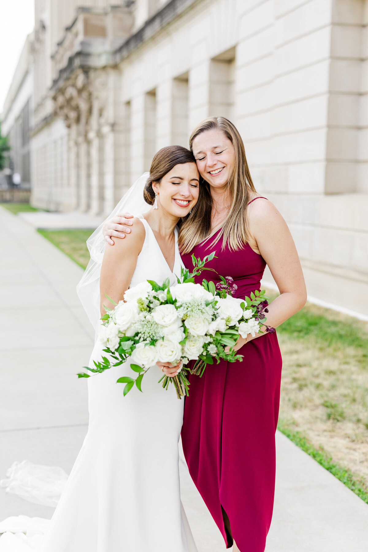 17_bride_and_bridesmaid_smiling_with_heads_togehter_bhld_bridesmaid_dress_red