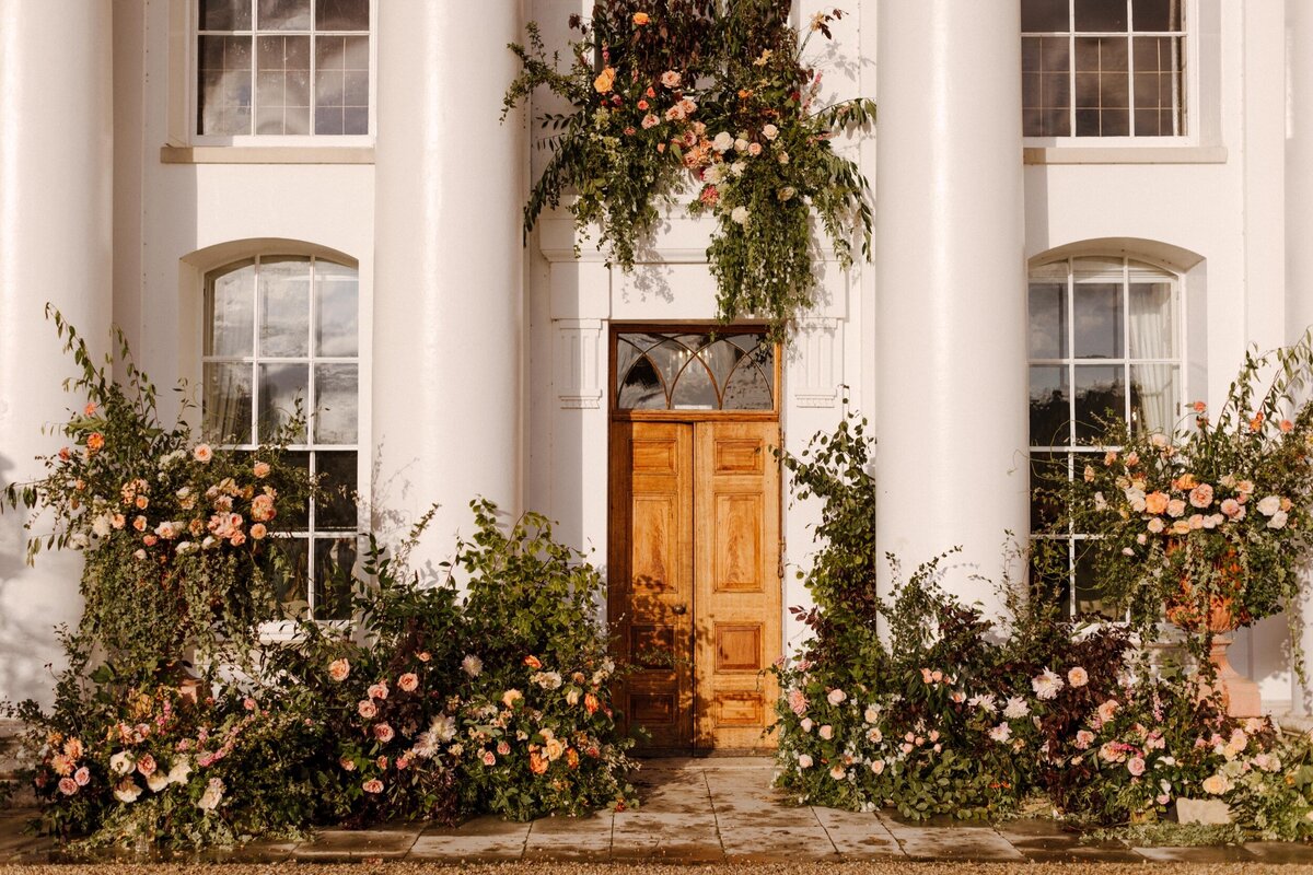 Garden wedding ceremony with colourful floral arch.