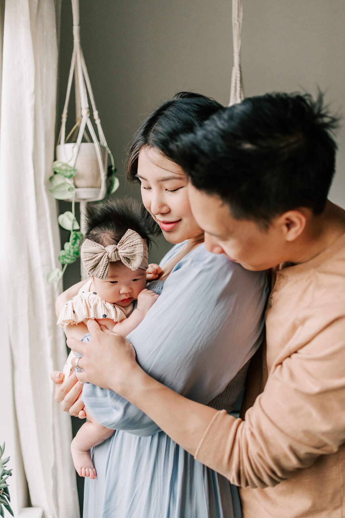 A dad holding his wife and baby girl during their newborn session