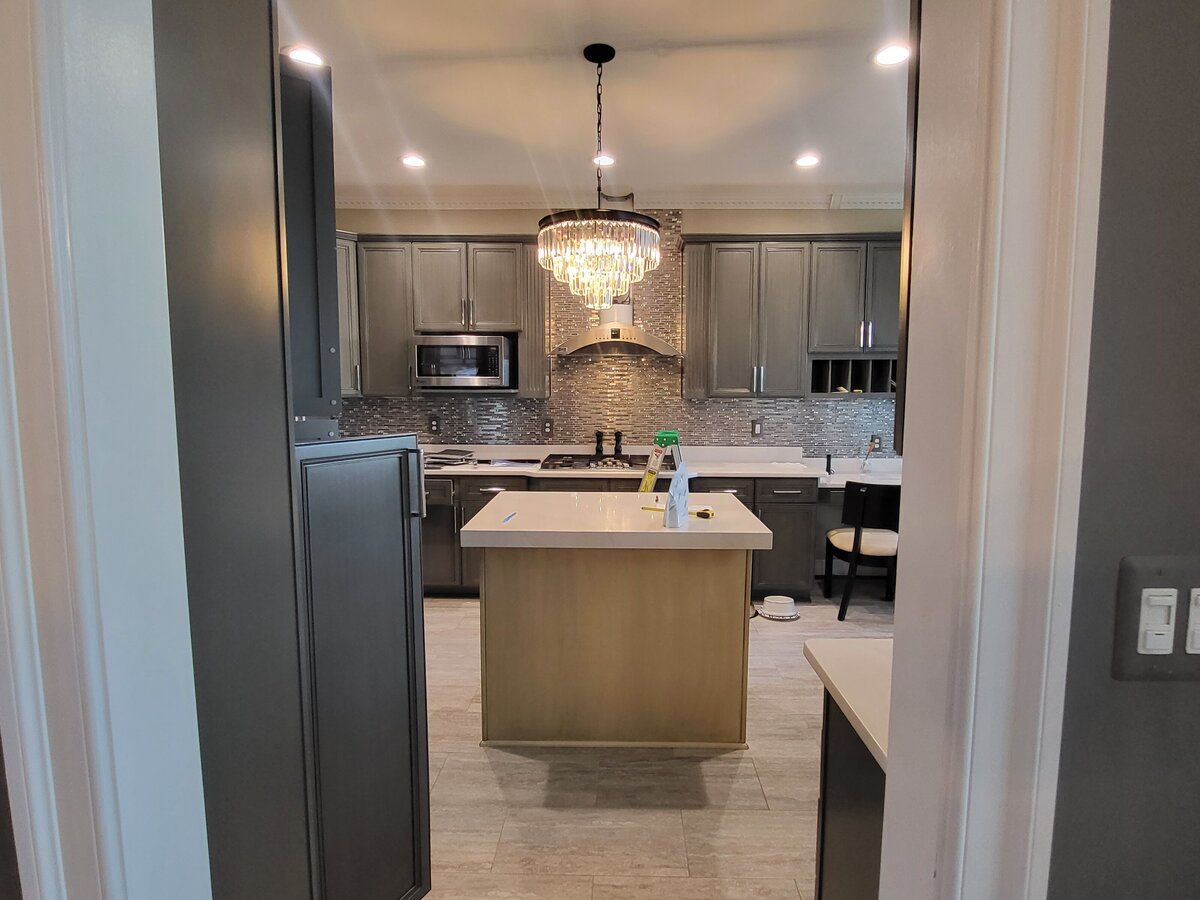 Kitchen with island that was the wrong size for the kitchen which would be removed along with the glass, metal and crystal tile backsplash surrounded by grey green cabinets