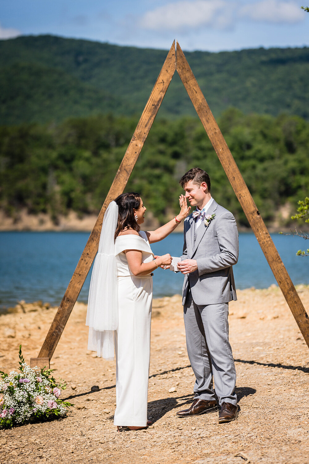 A marrier wipes a tear away from her partner’s face as they each read vows to one another under a triangle arch on Carvin’s Cove in Roanoke, Virginia.