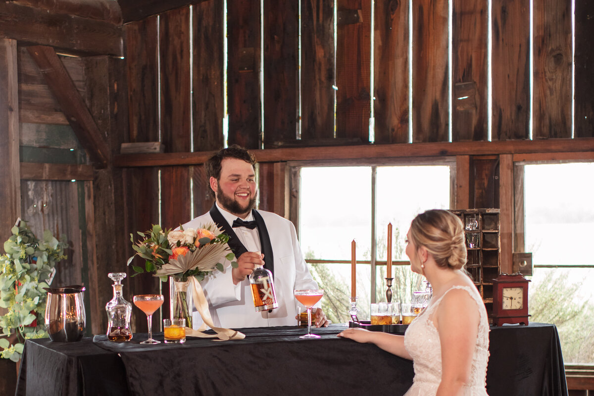 man in white tuxedo serves bar drink to bride at The 1850 Settlement