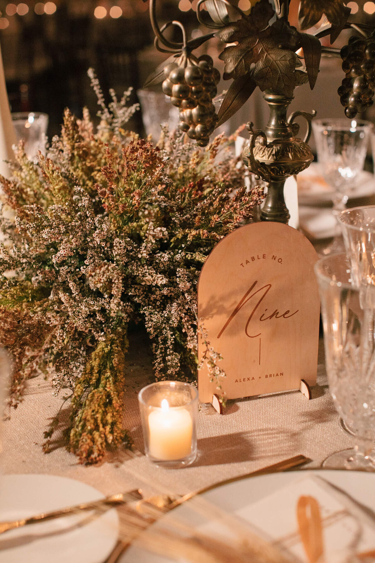 Dried flowers with wood table numbers and votive candles.