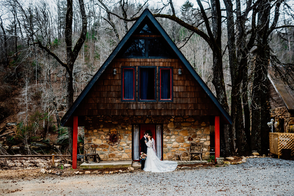 a bride and groom in front of a cabin in the pacific northwest