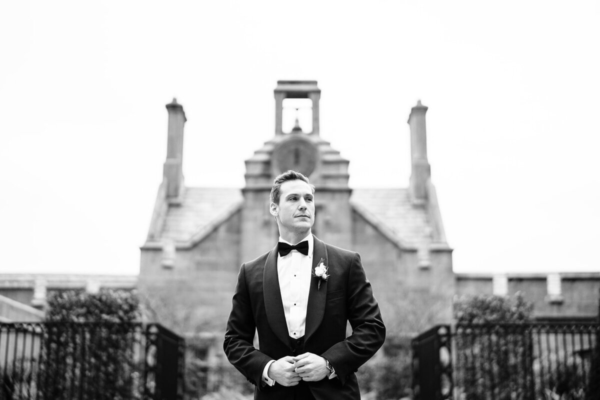 A black-and-white photograph of the groom in a Tuxedo in the grounds