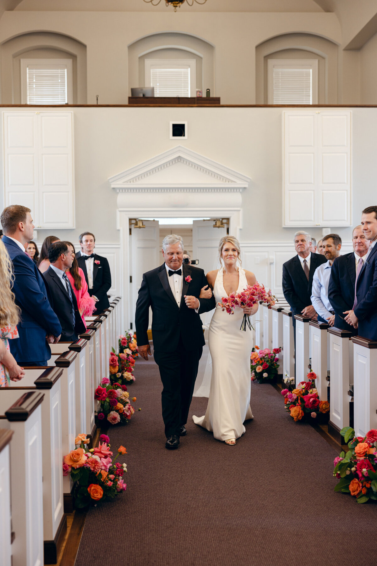 A wedding day photo of the bride walking down the aisle in her white wedding day dress