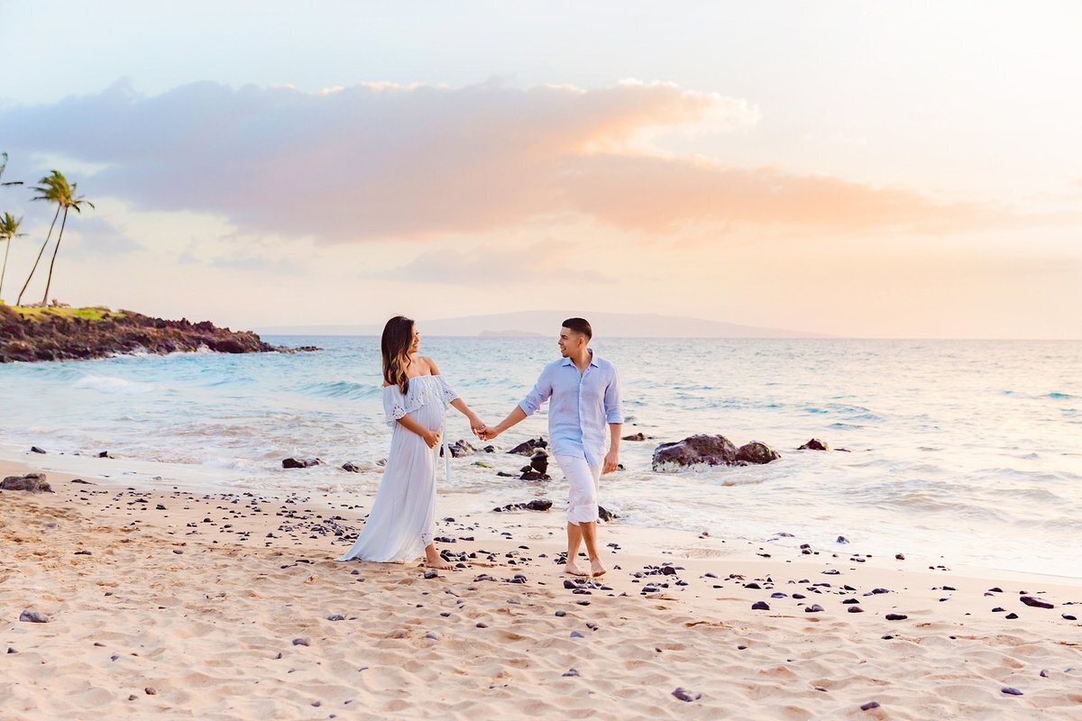 Expecting couple walk hand-in-hand down Ulua Beach on Maui during their babymoon vacation portraits by Love + Water