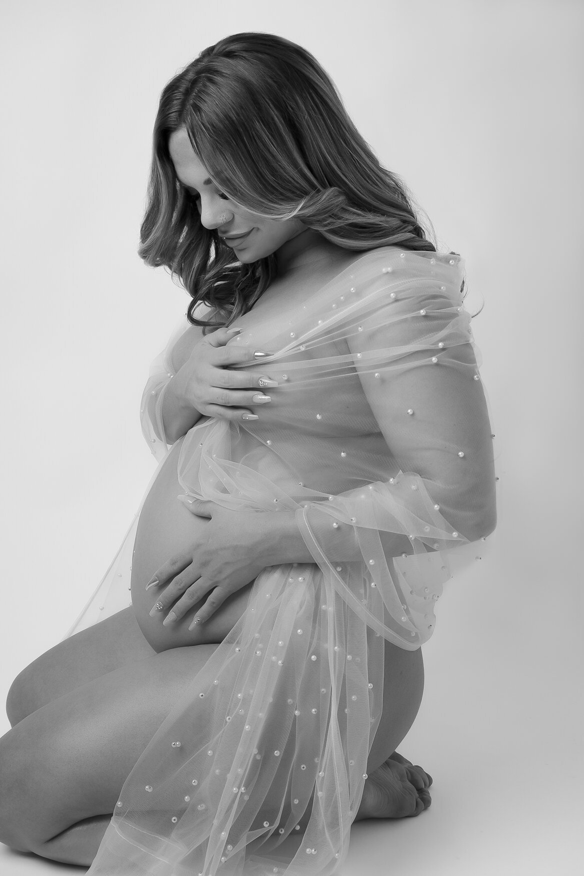 A woman sitting on her knees touching gently her baby bump