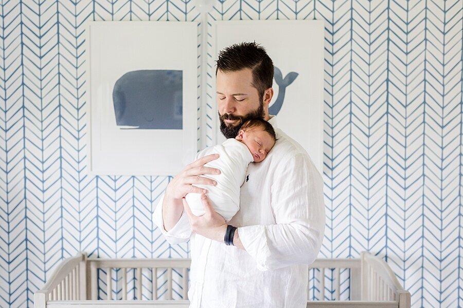 dad cuddling baby in front of crib by DC Newborn Photographer Emily