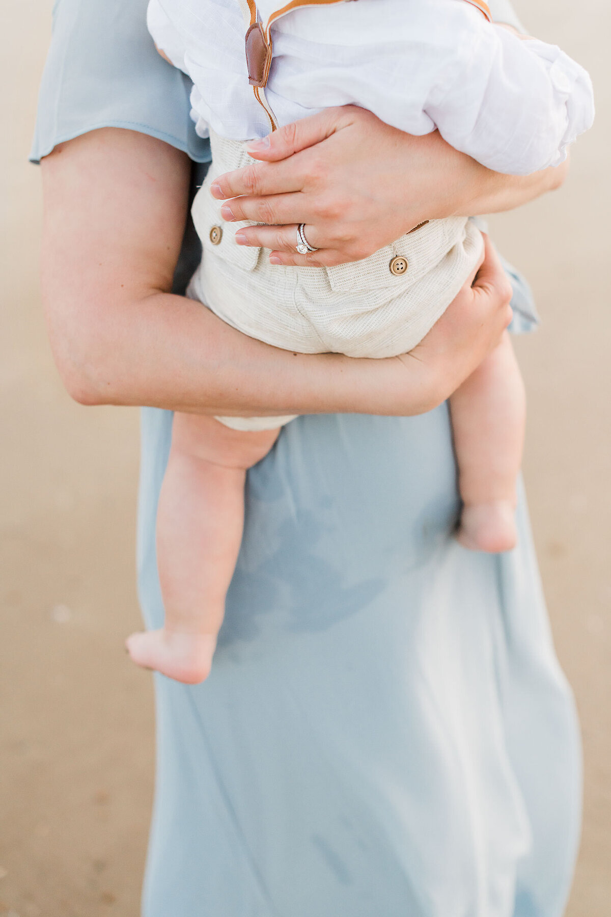 a woman in a blue dress is carrying her son on her hip