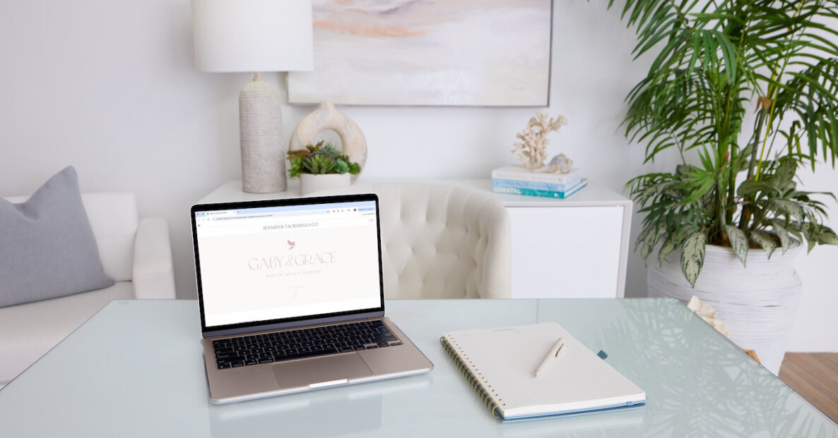 Laptop displaying the Gaby & Grace case study and portfolio with a notebook and pen beside it—highlighting a real branding and website project by Jennifer Taormina & Co.