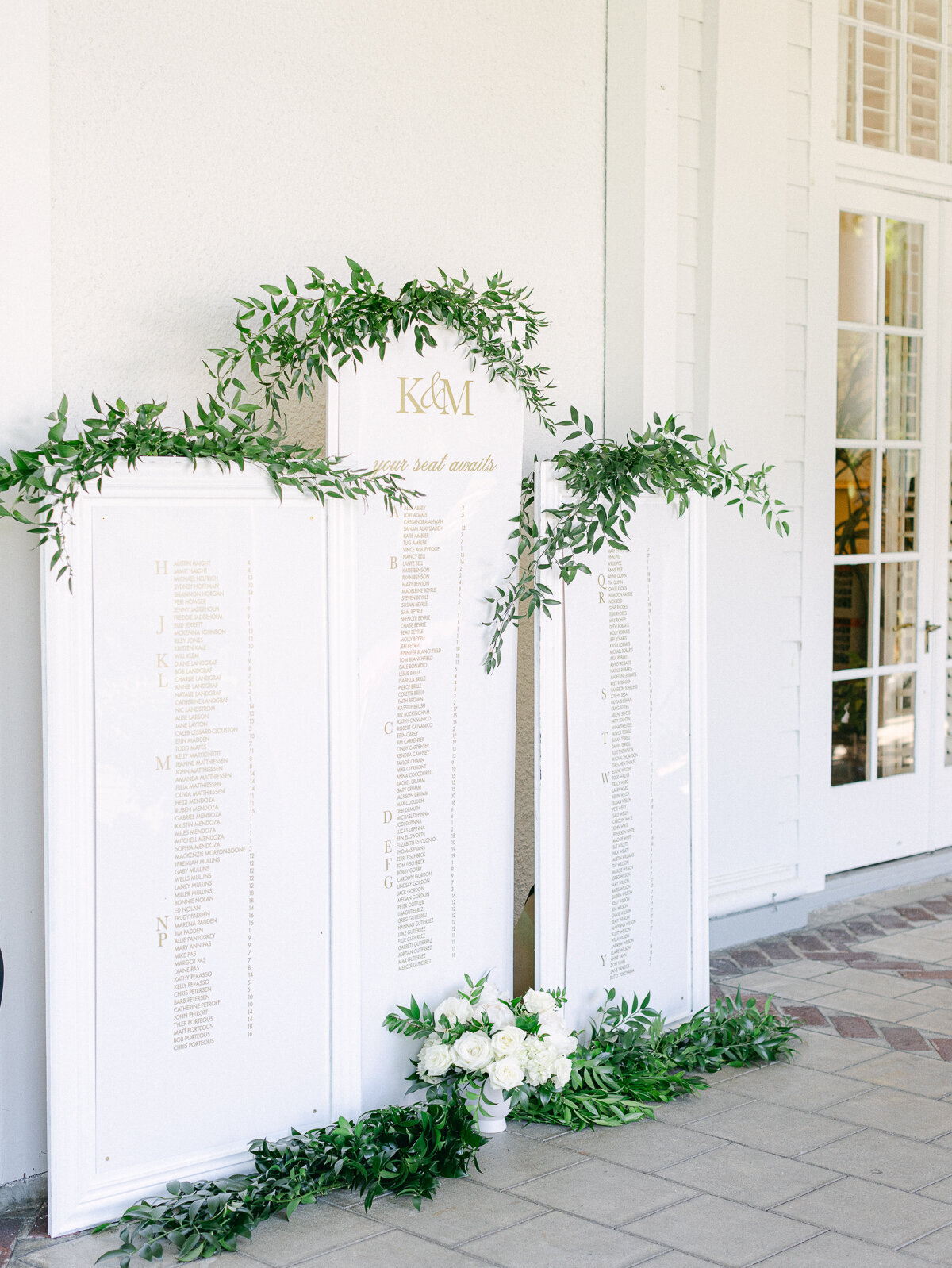Elegant white seating chart with greenery