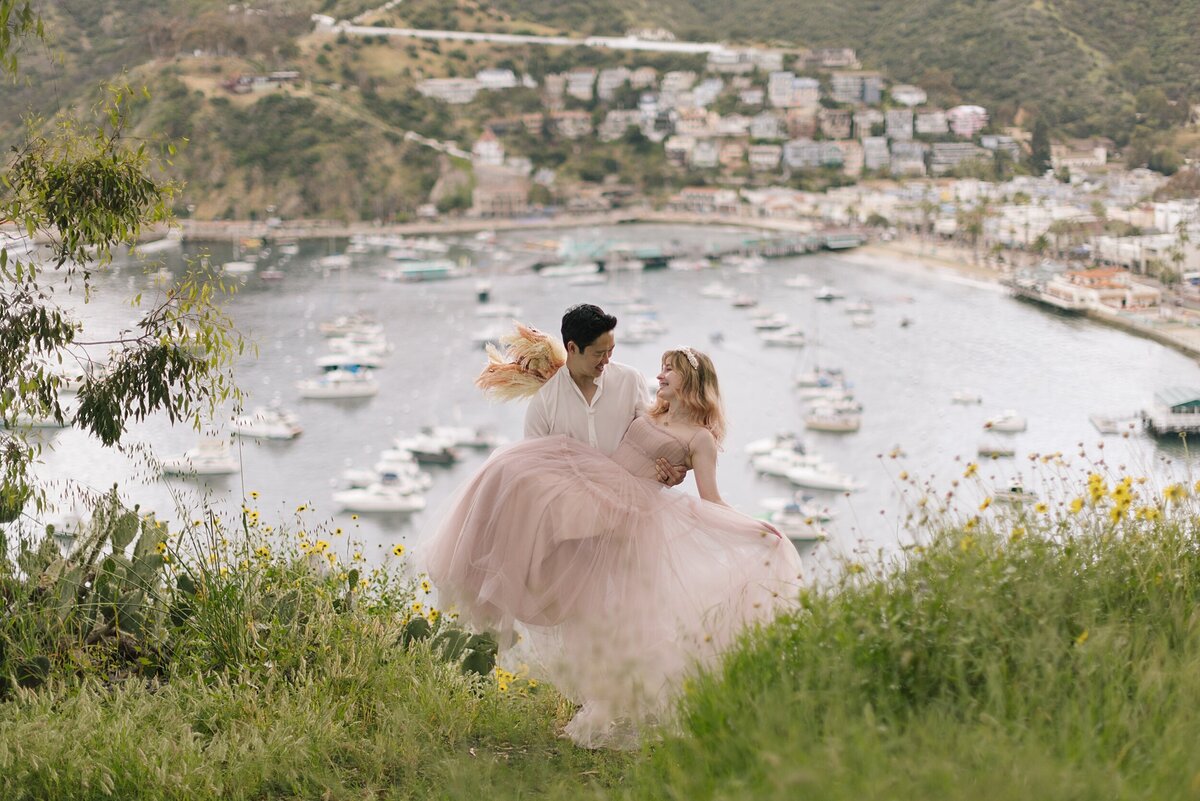 A groom holds the bride in Catalina Island on their wedding day.