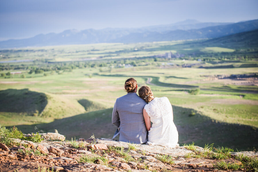 Two brides sit and look out at a vast landscape.