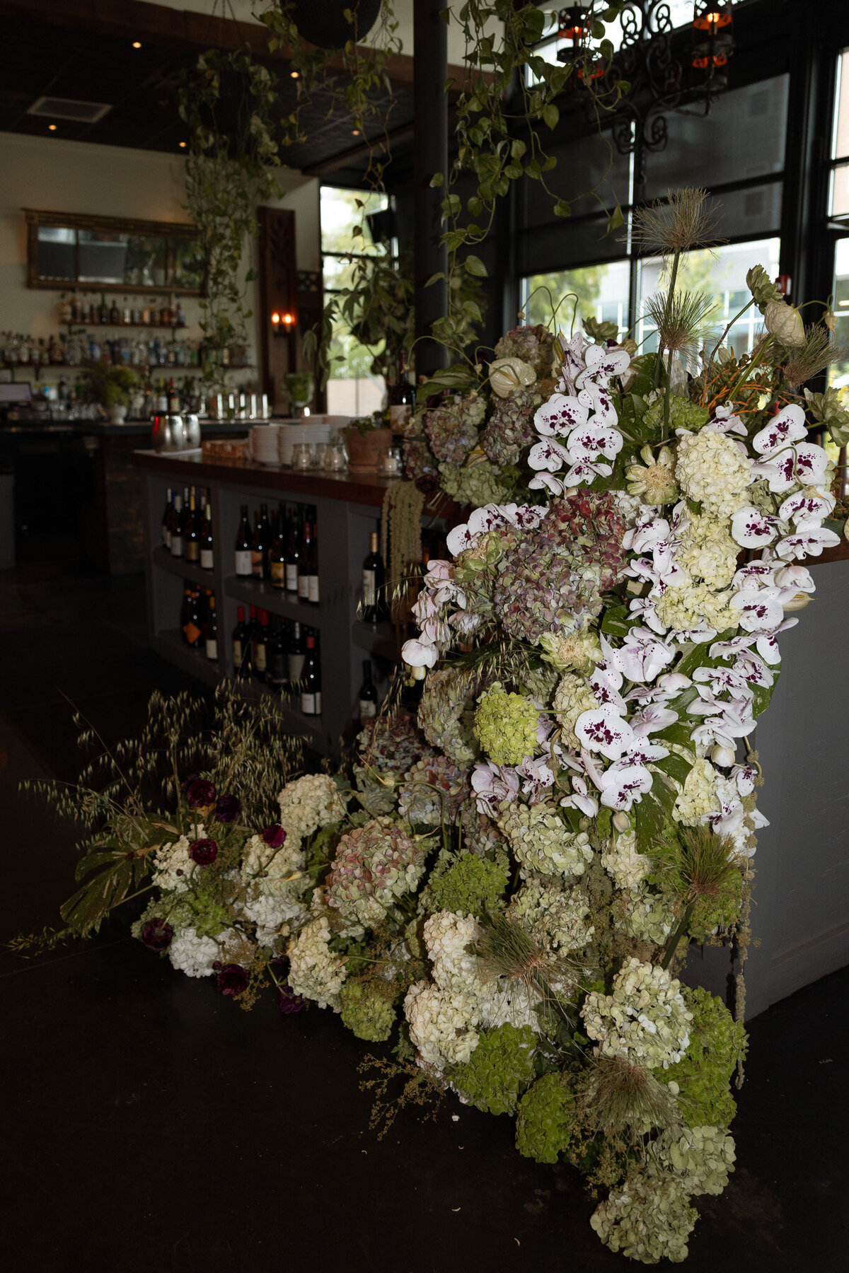 Dramatic florals cascade over a wine bar shot with a flash at the Peninsula in downtown Nashville, TN.