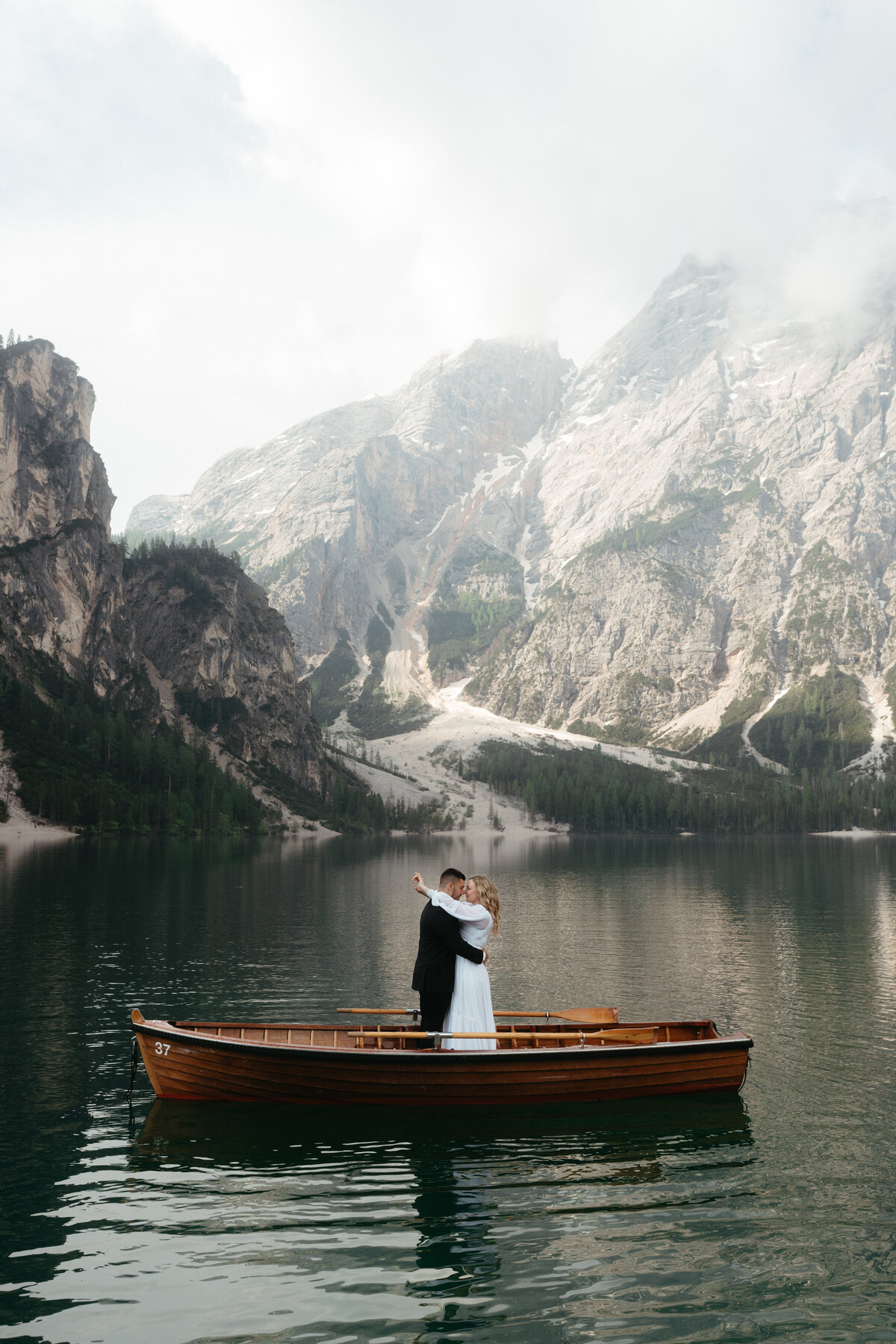 Dolomites Elopement with bride and groom standing in a rowboat on Lago di Braies with mountains in the back