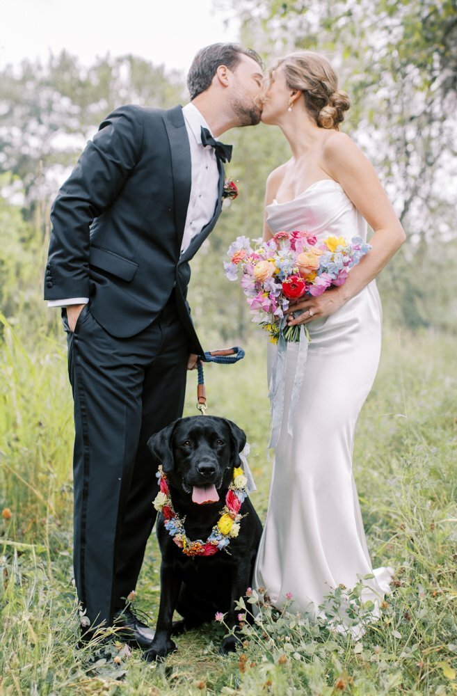 couple sharing a kiss with their dog watching during their Alberta wedding photographed by Calgary wedding photographer team Heidrich Photography