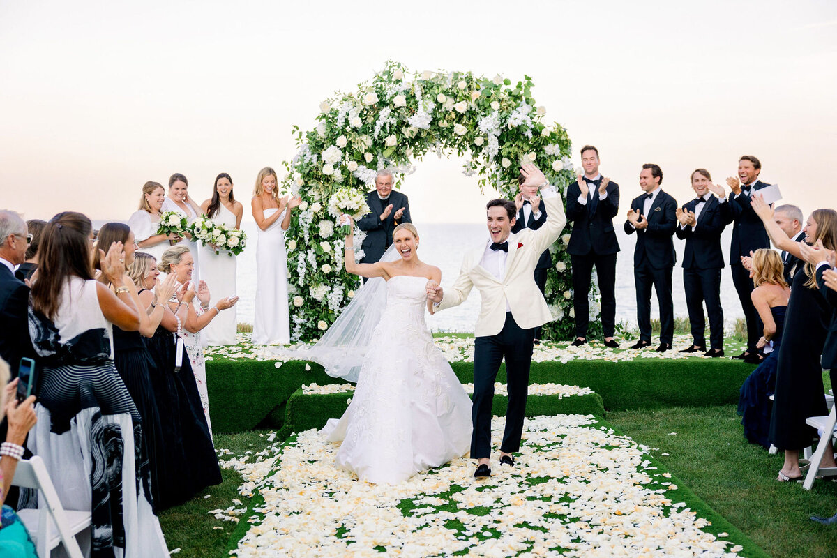 The bride and groom walking down the aisle of flowers after getting married.