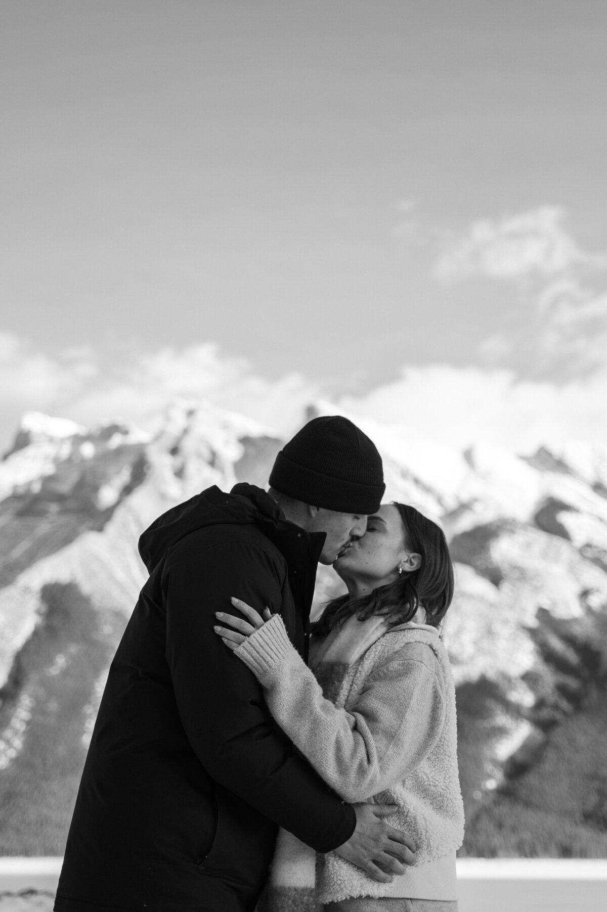Couple embracing and kissing after getting engaged during a Banff proposal shoot in Lake Minnewanka.