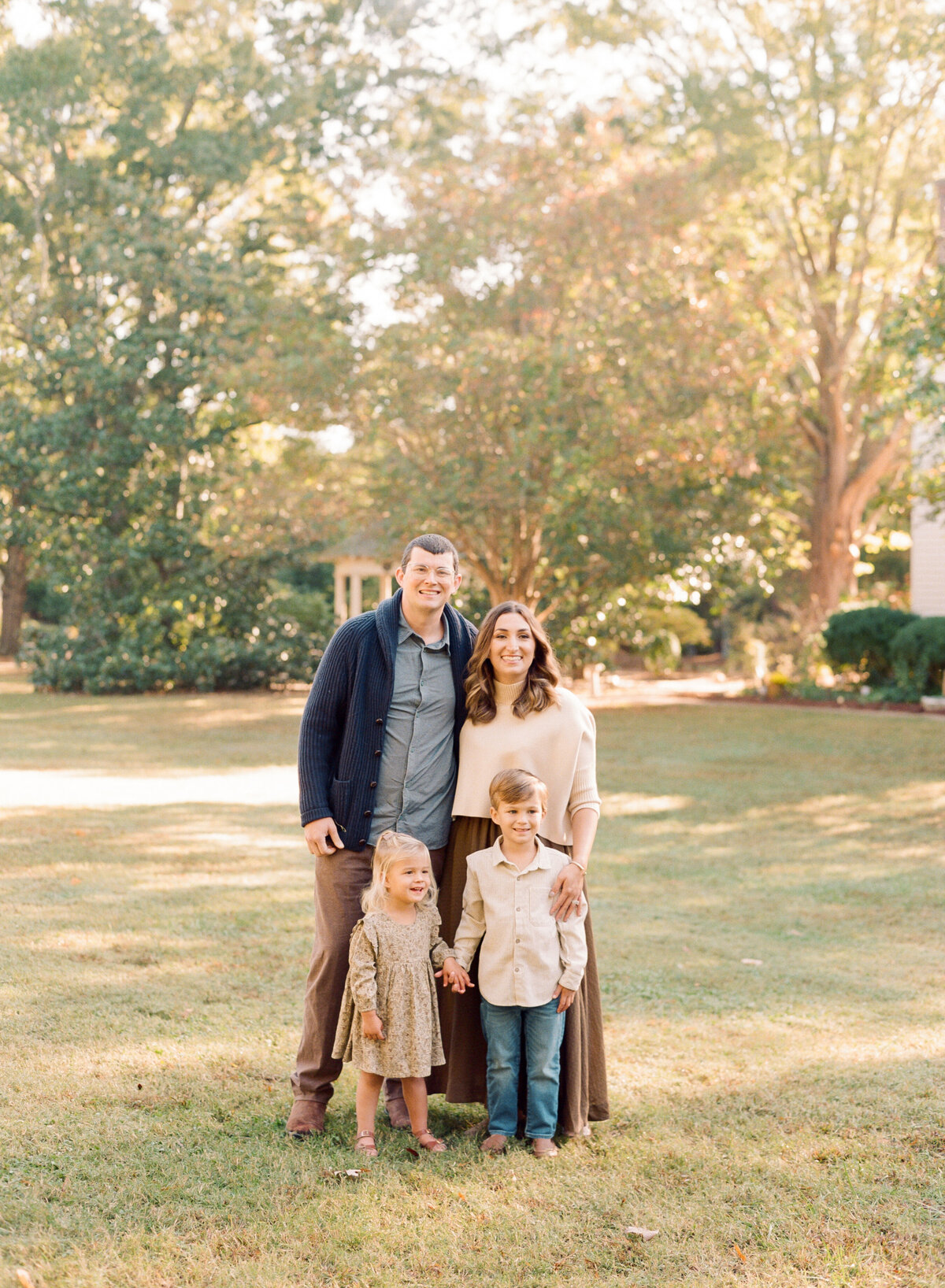 Family smiles for a portrait during their family session in Raleigh NC. Family walking during their family portrait session in Wake Forest, NC. Photographed by Raleigh family photographer A.J. Dunlap Photography.