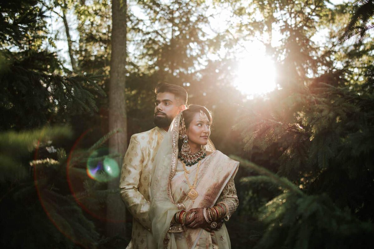 South Asian bride and groom embracing each other surrounded by greenery in Philadelphia as the sun sets.