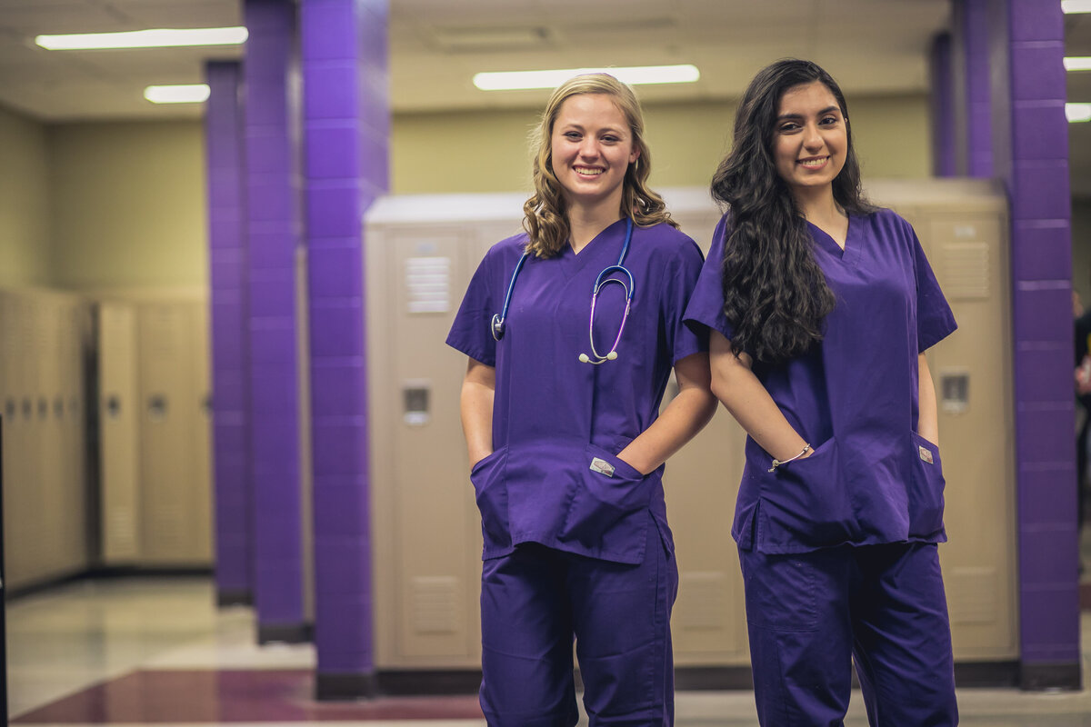 Two female nursing students in purple scrubs