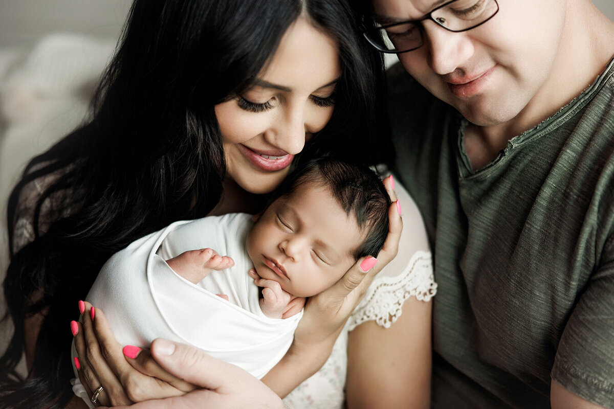 mom and dad holding baby together