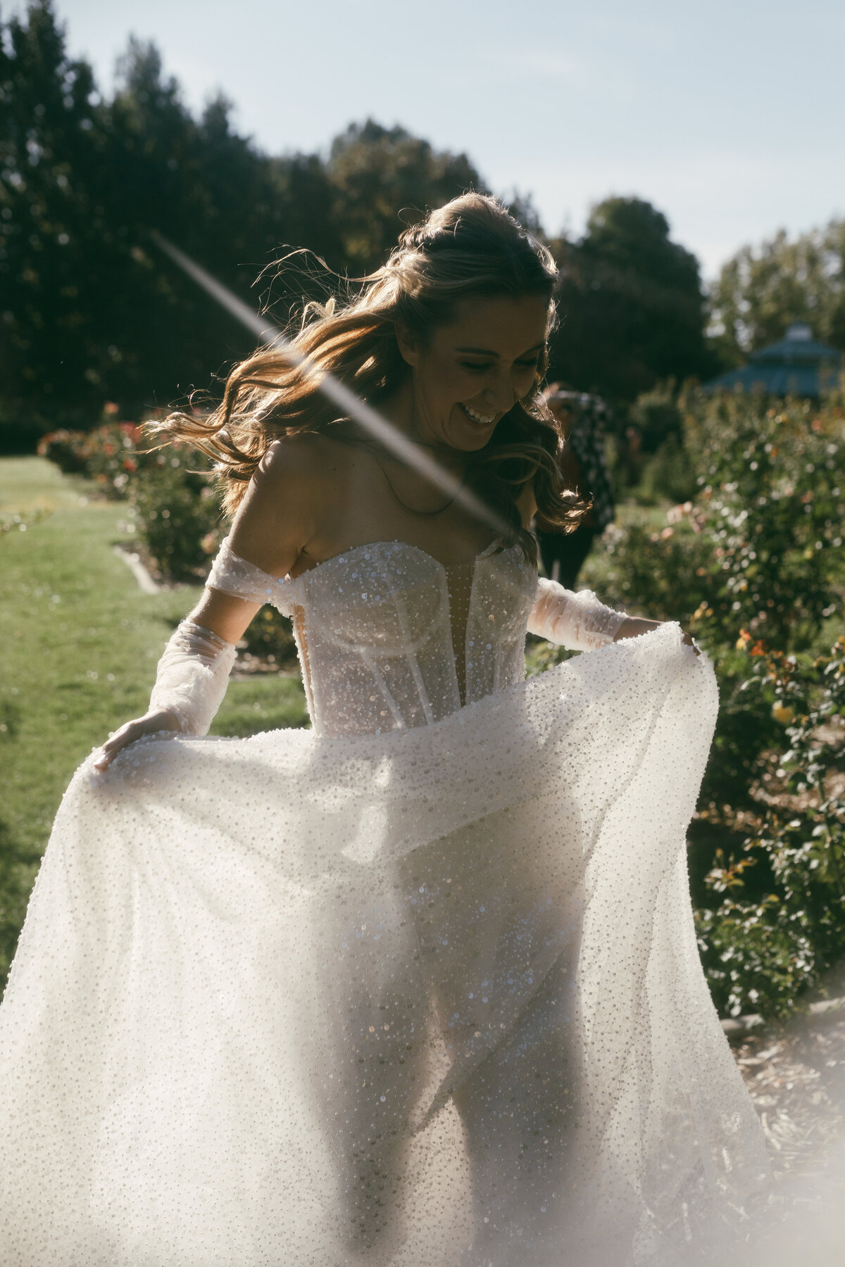 Bride running through rose garden with sparkle off shoulder fairy tale inspired wedding gown