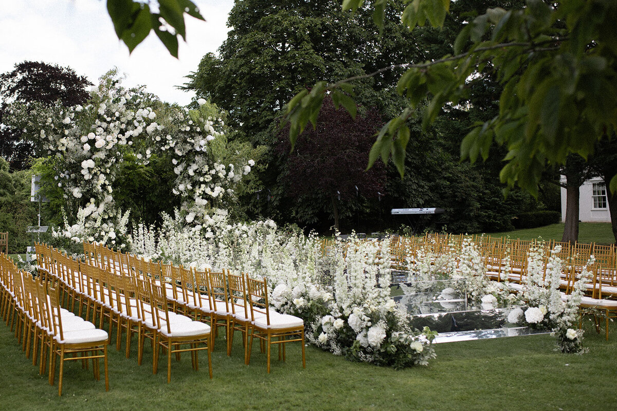 Outdoor ceremony setup featuring a mirrored aisle and all-white wedding flowers at Monkey Island Estate