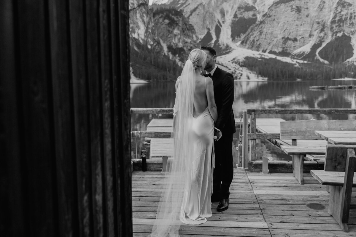 Black and white photo of bride and groom kissing on dock