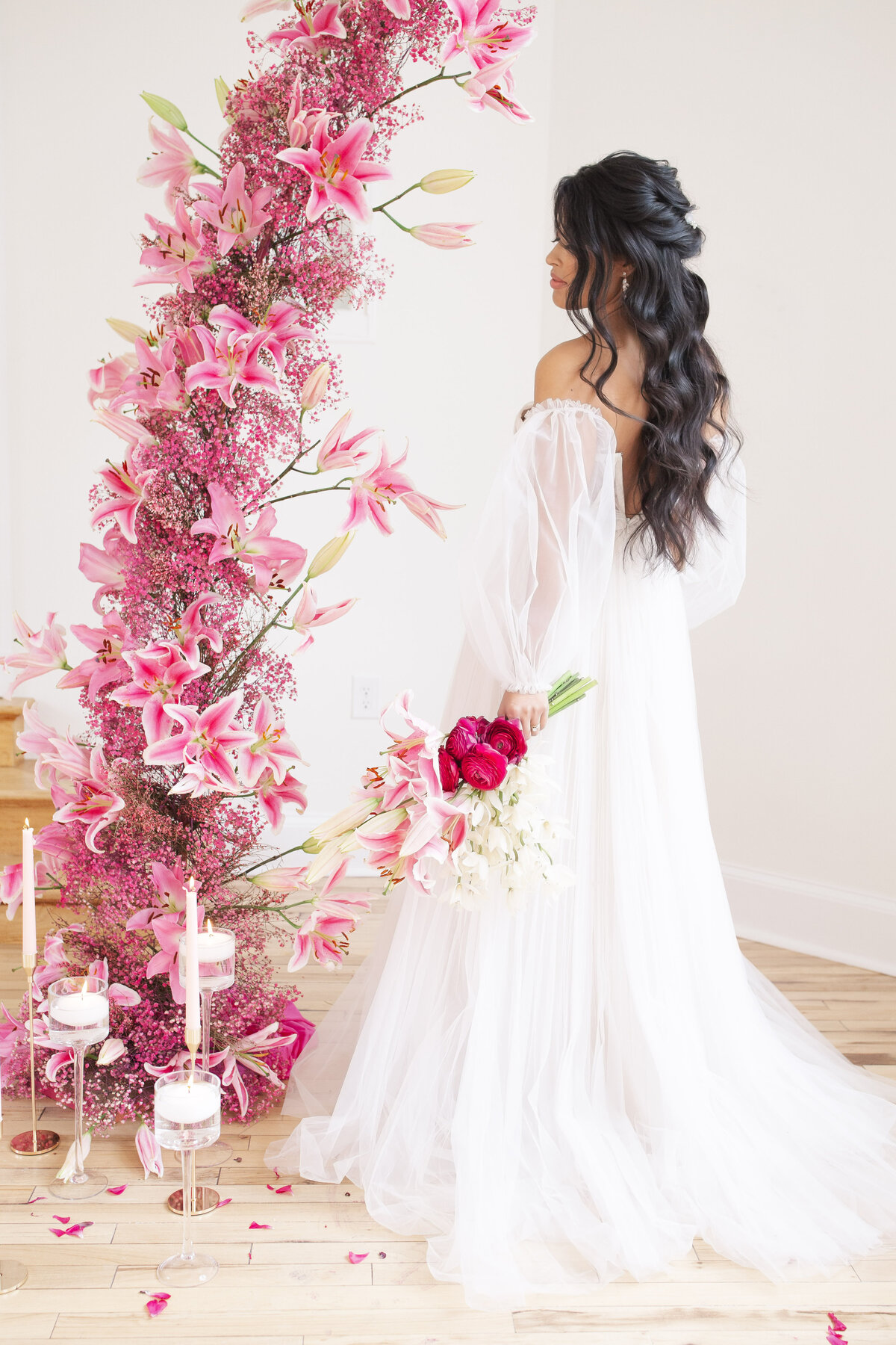 bride next to floral arch of pink and white lilies
