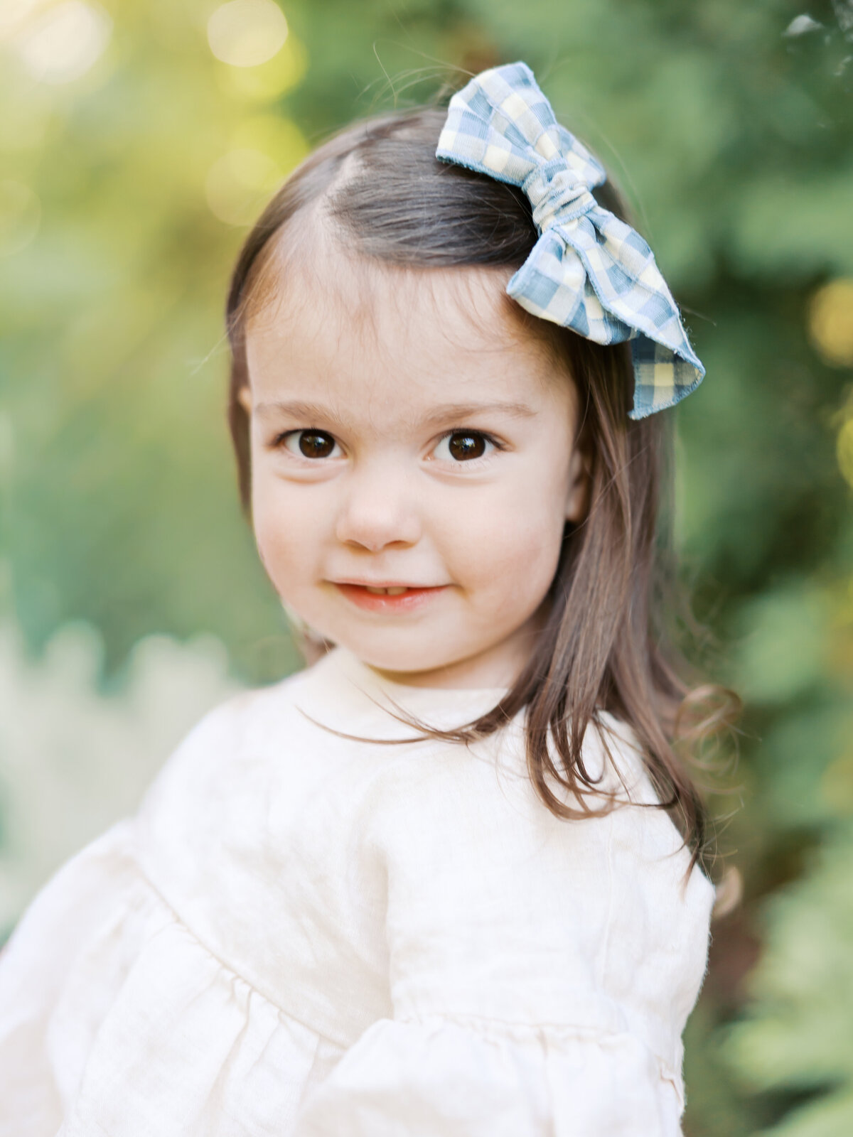 Girl with big bow smiles for her minneapolis family photography session with angela watts photography.