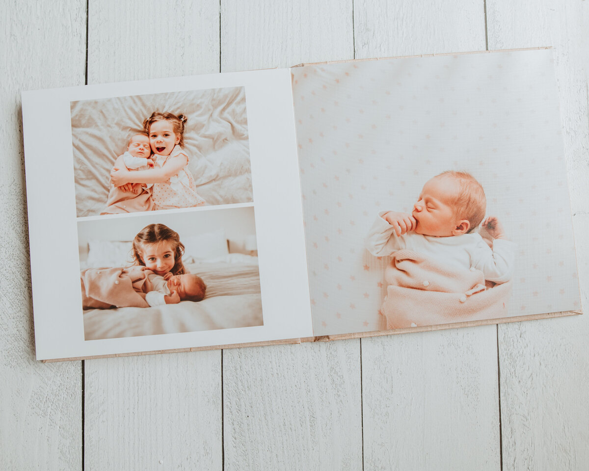 A newborn session fine art photo album lays open on wood