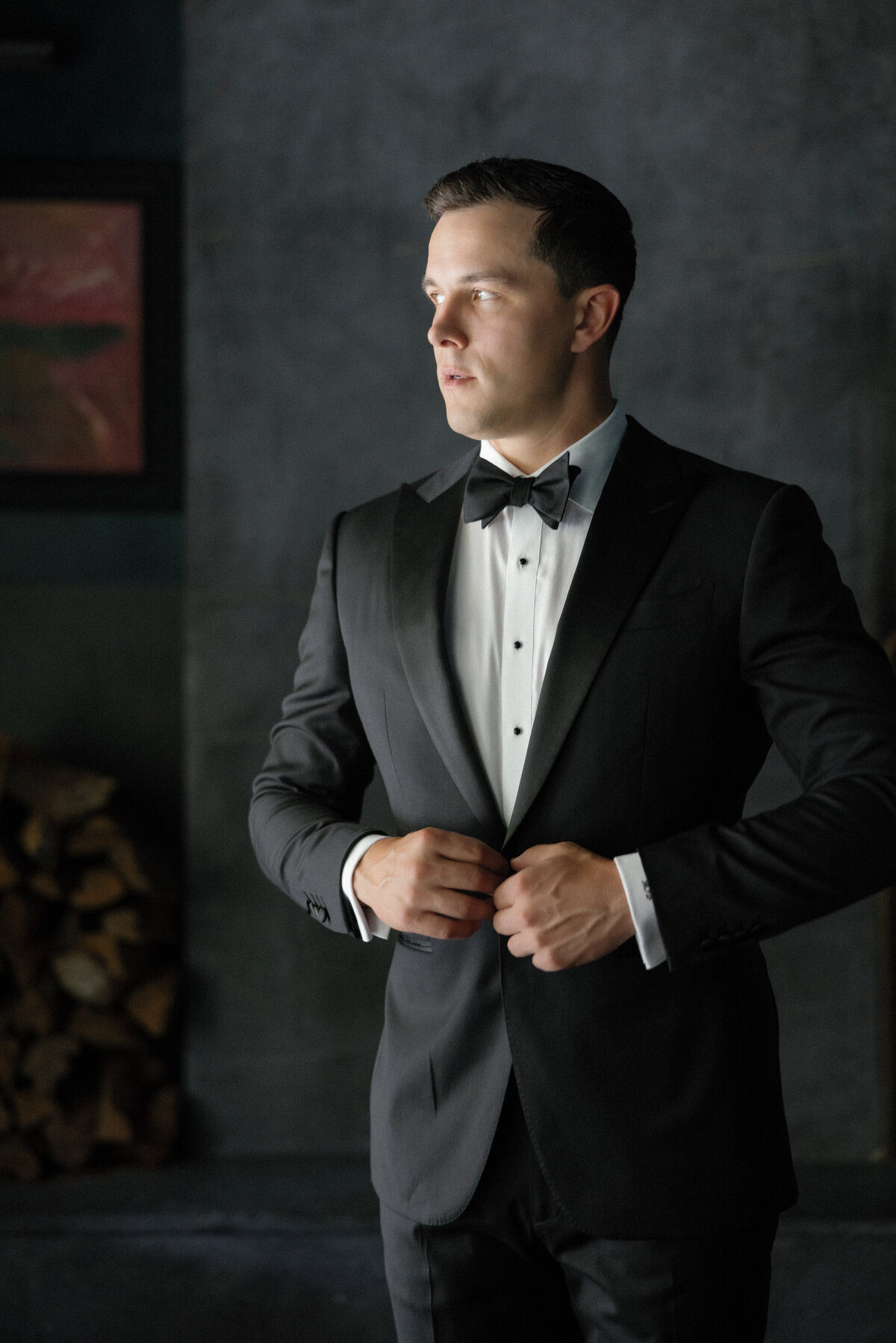 Groom buttoning tuxedo jacket