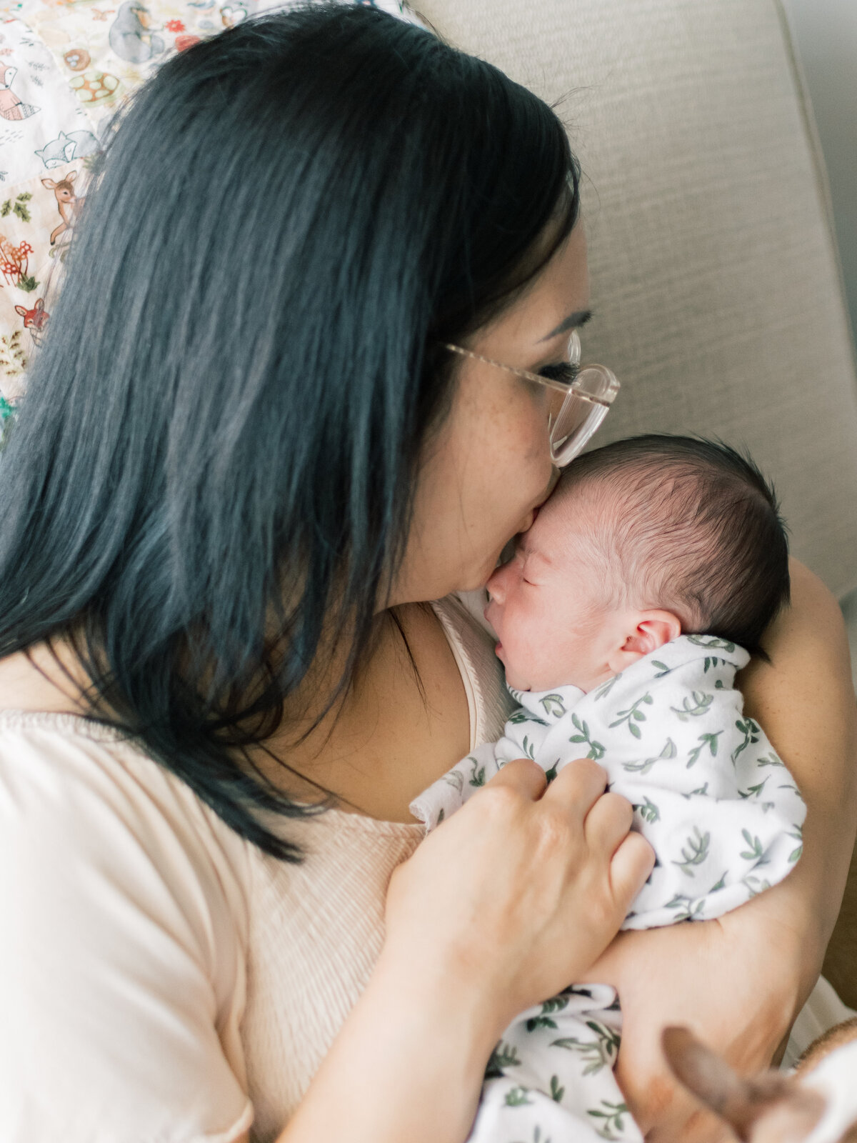 Mom kissing the top of newborn baby boys head.