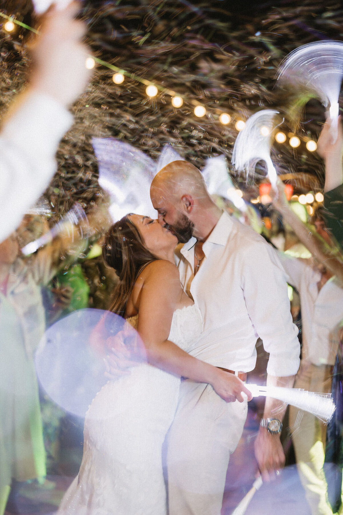 Bride and groom kissing during grand exit with bubbles and glow wands at Hilton Beachfront Resort Santa Barbara