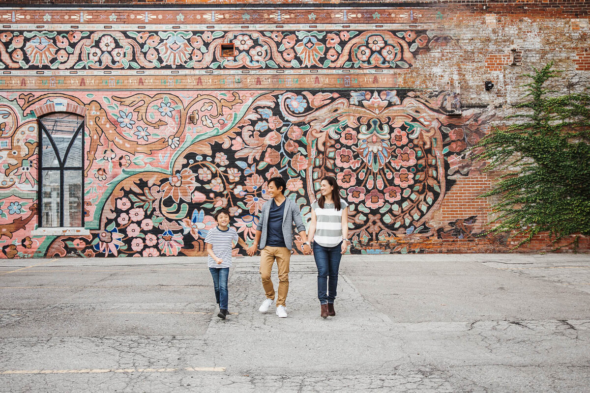 Family of 3 walking in front of colourful mural during family photo session