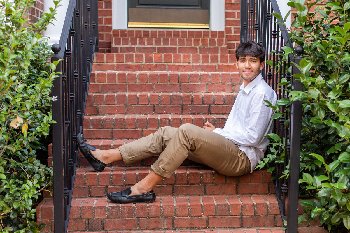 high school senior boy sitting on house front steps wearing beige pants and a white shirt Atlanta GA
