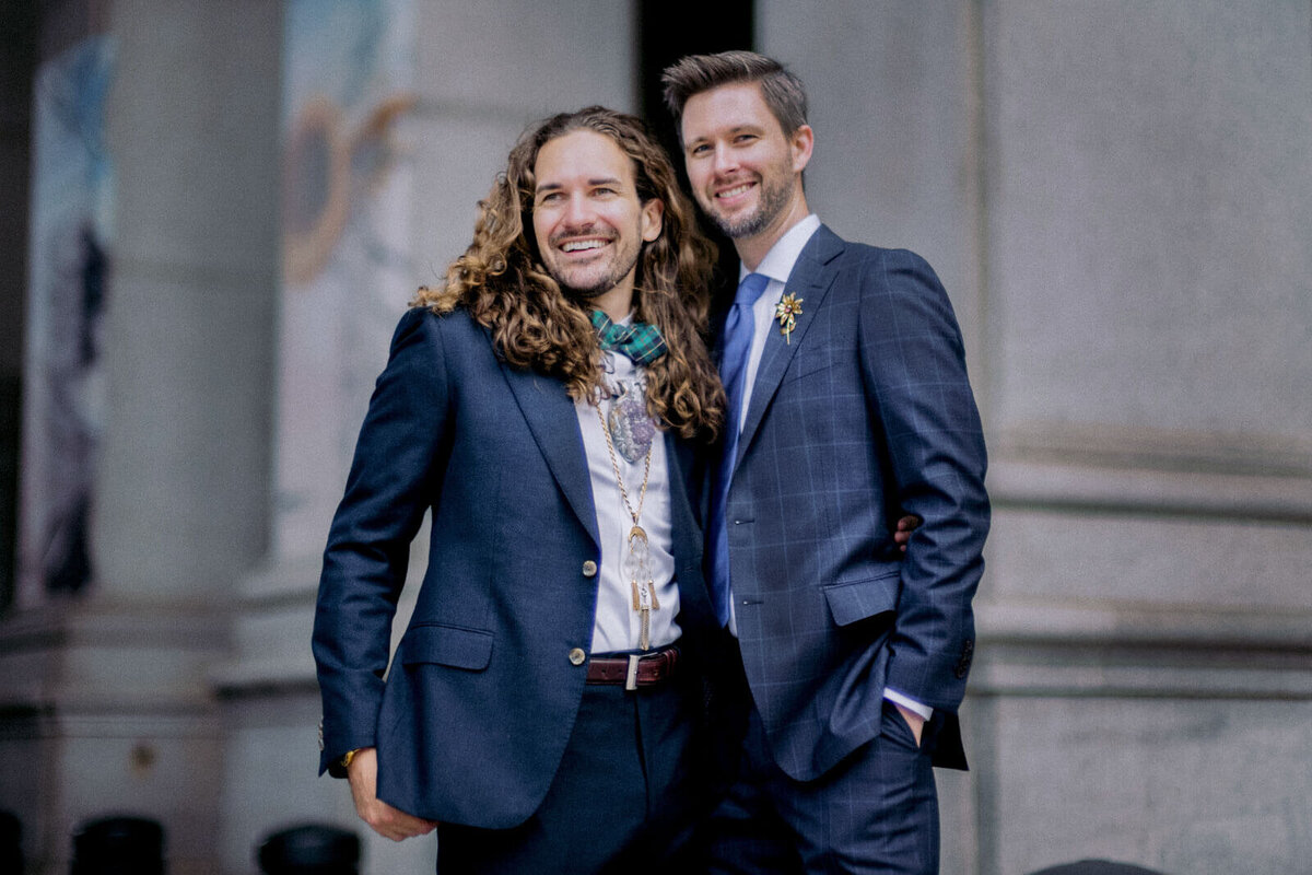 The two grooms are in front of NYC City Hall. Elopement Image by Jenny Fu Studio