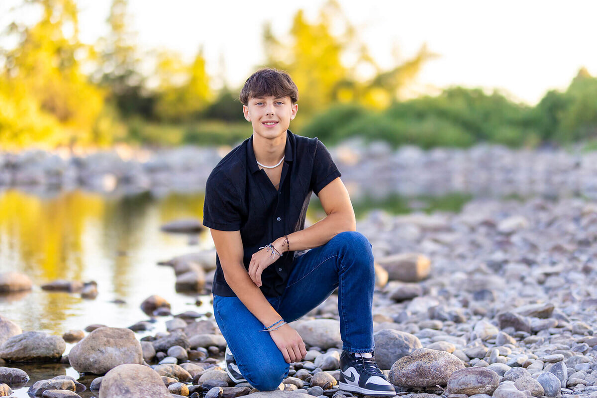 Boy portrait kneeling next to Spokane River 