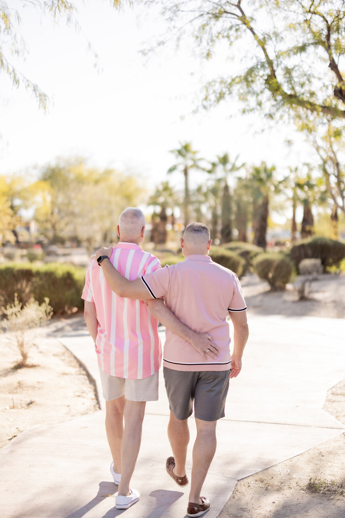 Couple walking away holding hands, wrapped in soft light with mid-century architecture in the distance.