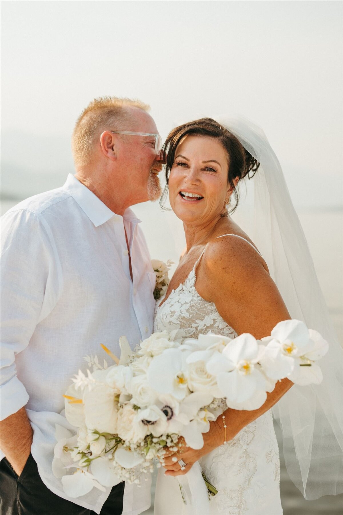 Portrait of a married couple holding white flowers from Polka Dot Door Flowers in Osoyoos
