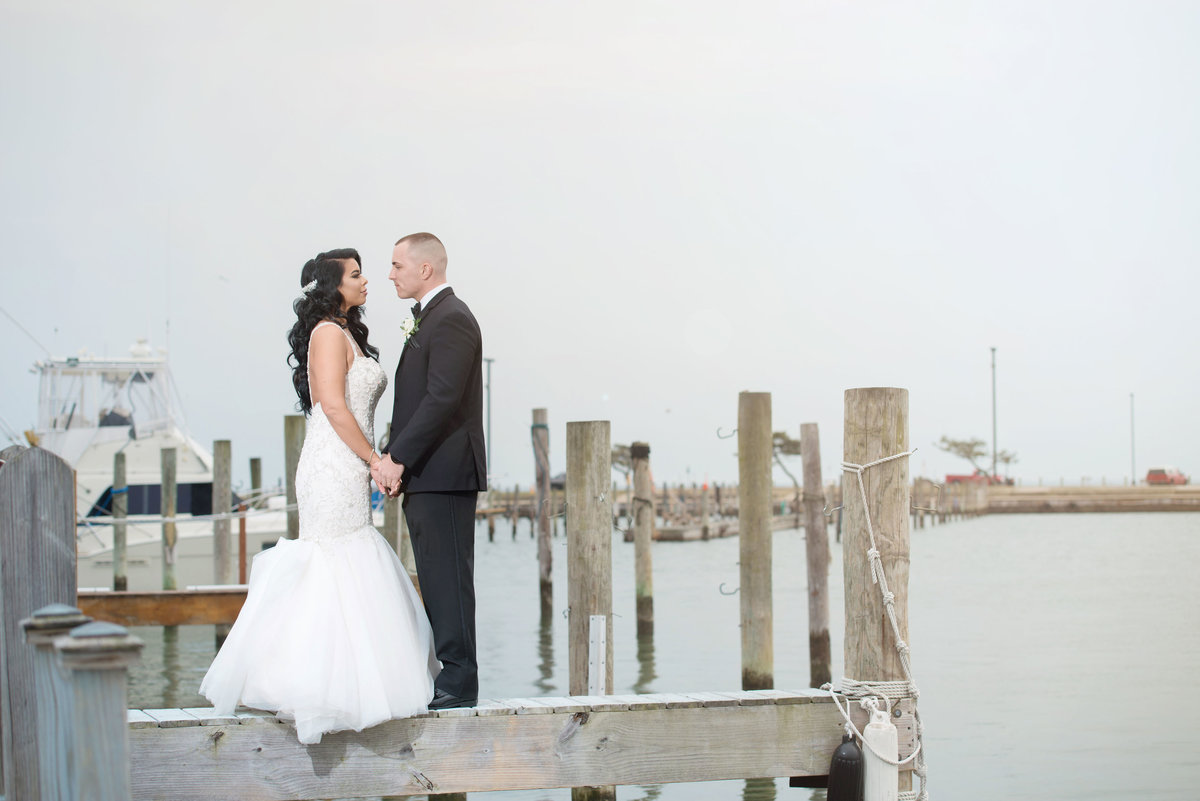 bride and groom standing on dock holding hands at Captain Bills